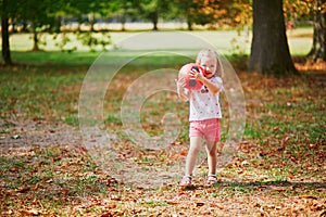 Adorable toddler girl playing soccer in park