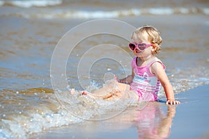 Adorable toddler girl splashing in ocean waves