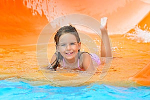 Adorable toddler girl on water slide at aquapark