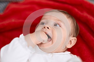 Adorable toddler lying on sofa bitting fingers at home