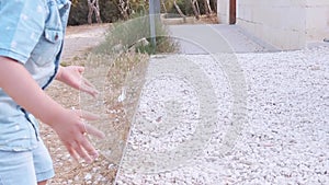 Adorable toddler picking up white stones pebbles and stepping on it in the park