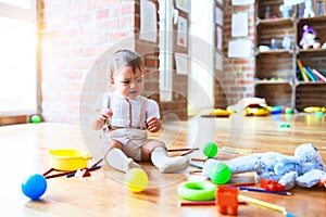 Adorable toddler playing around lots of toys and crying at kindergarten