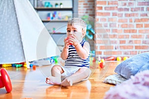 Adorable toddler playing around lots of toys at kindergarten