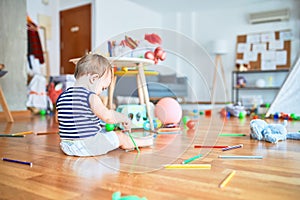 Adorable toddler playing around lots of toys at kindergarten