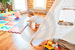 Adorable toddler playing around lots of toys at kindergarten