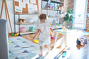 Adorable toddler playing around lots of toys at kindergarten