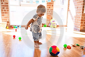 Adorable toddler playing with balls around lots of toys at kindergarten