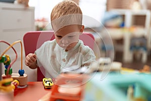 Adorable toddler playing with car toy sitting on table at kindergarten