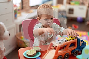 Adorable toddler playing with car toy sitting on table at kindergarten