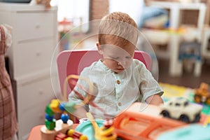 Adorable toddler playing with car toy sitting on table at kindergarten