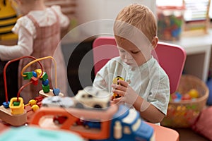 Adorable toddler playing with car toy sitting on table at kindergarten