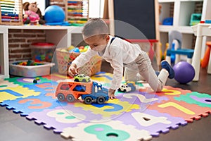 Adorable toddler playing with truck toy sitting on floor at kindergarten