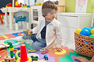 Adorable toddler playing with truck toy sitting on floor at kindergarten