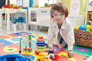 Adorable toddler playing with truck toy sitting on floor at kindergarten