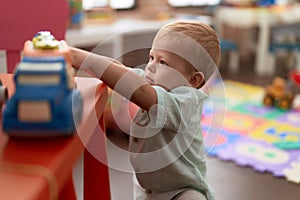 Adorable toddler playing with truck toy standing at kindergarten