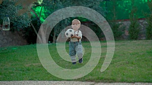 Adorable toddler plays with soccer ball walking on grass