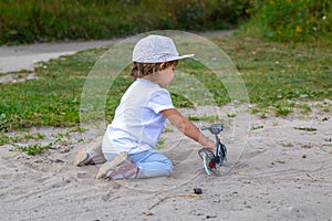 adorable toddler plays with a toy bike in nature. child on all fours in the sand on the lawn