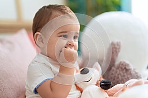 Adorable toddler sitting on sofa bitting fingers at home