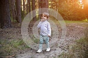 Adorable toddler walks in the woods in sunshine