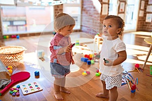 Adorable toddlers playing around lots of toys at kindergarten photo