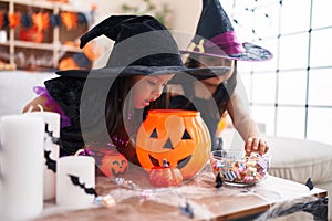 Adorable twin girls having halloween party holding candies at home