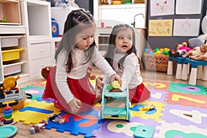 Adorable twin girls playing with toys at kindergarten