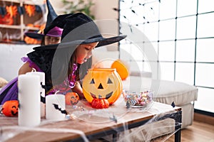 Adorable twin girls wearing halloween costume looking on pumpkin basket at home