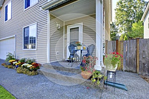 Adorable white house with nice small porch and lots of flowers..