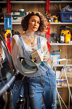 adorable woman car mechanic in blue overalls with a book-instruction