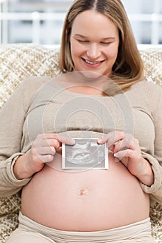 Adorable woman showing an echography to the camera photo