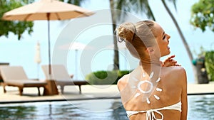 Adorable woman taking sun bath close to pool