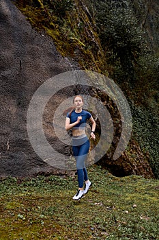 Adorable woman warms up in park mountains before jogging. Healthy lifestyle concept.