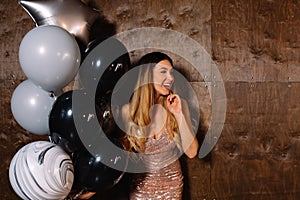 Adorable young blond with long hair wearing sparkly dress posing at camera with ballons and have fun, birthday party, happy
