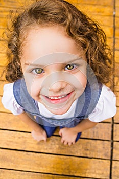 Adorable young brunette girl standing on wooden