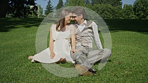 Adorable young couple in love sitting down on grass sharing an intimate moment