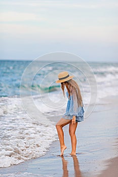 Adorable young girl with beautiful long hair enjoy tropical beach vacation. The girl on the seashore at sunset