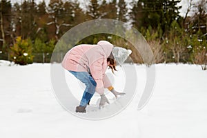 Adorable young girl building a snowman in the backyard. Cute child playing in a snow