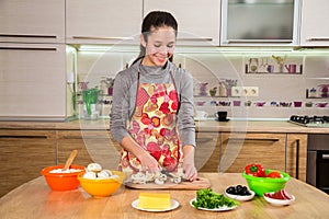 Adorable young girl cutting the mushrooms in kitchen