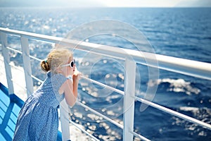 Adorable young girl enjoying ferry ride staring at the deep blue sea. Child having fun on summer family vacation in Greece