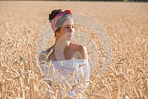 Adorable young girl on golden wheat field