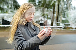 Adorable young girl having fun in beautiful winter park. Cute child playing in a snow