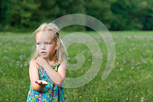 Adorable young girl holding grasshopper