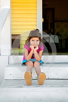 Adorable Young Girl Sits on Painted White Steps with Her Chin in