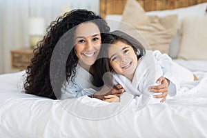 Adorable young mother and cute daughter bonding on bed