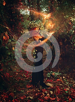 Adorable young redhair lady wizard conjures in the forest photo