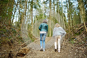 Adorable young sisters having fun during a hike in the woods on beautiful sunny spring day. Active family leisure with kids