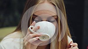 Adorable young woman drinks her coffee sitting in the cafe