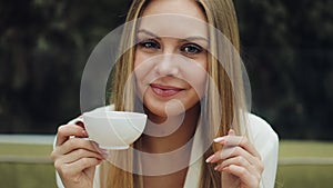 Adorable young woman drinks her coffee sitting in the cafe