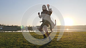 Adorable young woman playing running with her cute dog on nature near the lake.