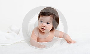 Adorably baby lie on towel in bed, white background. Happy childhood and healthcare concept